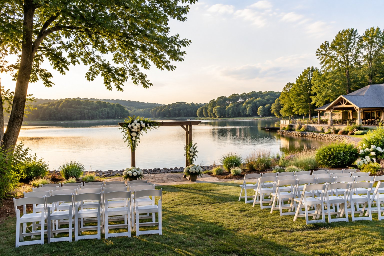 A lakeside wedding ceremony area with white chairs, a wooden arbor, and trees beside the water.